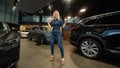 Young caucasian woman rejoices buying a car in a car dealership.
