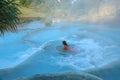 Young woman rests on a white stone ledge in invigorating thermal baths in Italy.