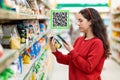 A young Caucasian woman scans the qr code on a package of cereals. Qr code icon above the product. Concept of modern technologies Royalty Free Stock Photo