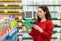 A young Caucasian woman scans the qr code on a shampoo bottle using her smartphone. Qr code icon above the product. In the Royalty Free Stock Photo