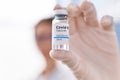 Young caucasian woman scientist holding covid dose vaccine at laboratory