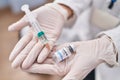 Young caucasian woman scientist holding syringe and covid dose vaccine at laboratory