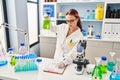 Young caucasian woman scientist measuring liquid writing on document at laboratory Royalty Free Stock Photo