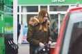 Young caucasian woman at self-service gas station, hold fuel nozzle and refuel the car with petrol, diesel, gas. Pretty Royalty Free Stock Photo