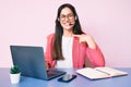 Young caucasian woman sitting at the desk wearing call center agent headset working using laptop pointing finger to one self Royalty Free Stock Photo