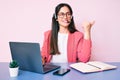 Young caucasian woman sitting at the desk wearing call center agent headset working using laptop pointing thumb up to the side Royalty Free Stock Photo