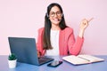 Young caucasian woman sitting at the desk wearing call center agent headset working using laptop smiling happy pointing with hand Royalty Free Stock Photo