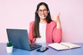 Young caucasian woman sitting at the desk wearing call center agent headset working using laptop smiling happy and positive, thumb Royalty Free Stock Photo