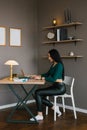 Young Caucasian woman is sitting at home at her desk with a laptop Royalty Free Stock Photo