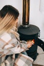 Young caucasian woman sitting in living room near fireplace in country house and warms his hands Royalty Free Stock Photo