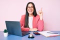 Young caucasian woman sitting at the recepcionist desk working using laptop pointing finger up with successful idea