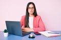 Young caucasian woman sitting at the recepcionist desk working using laptop with serious expression on face