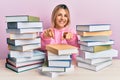 Young caucasian woman sitting on the table with books pointing to you and the camera with fingers, smiling positive and cheerful Royalty Free Stock Photo