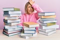 Young caucasian woman sitting on the table with books surprised with hand on head for mistake, remember error