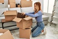 Young caucasian woman smiling confident putting books on cardboard box at new home Royalty Free Stock Photo