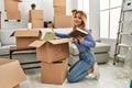 Young caucasian woman smiling confident putting books on cardboard box at new home Royalty Free Stock Photo