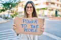 Young caucasian woman smiling happy holding power to the people banner cardboard walking at the city Royalty Free Stock Photo