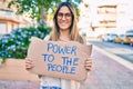 Young caucasian woman smiling happy holding power to the people banner cardboard walking at the city Royalty Free Stock Photo