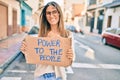 Young caucasian woman smiling happy holding power to the people banner cardboard walking at the city Royalty Free Stock Photo