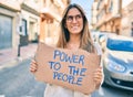 Young caucasian woman smiling happy holding power to the people banner cardboard walking at the city Royalty Free Stock Photo