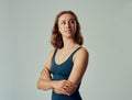 Young caucasian woman in sports bra looking over shoulder with arms crossed in studio Royalty Free Stock Photo