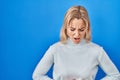 Young caucasian woman standing over blue background with hand on stomach because indigestion, painful illness feeling unwell Royalty Free Stock Photo