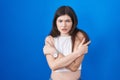 Young caucasian woman standing over blue background shaking and freezing for winter cold with sad and shock expression on face Royalty Free Stock Photo