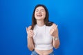 Young caucasian woman standing over blue background success sign doing positive gesture with hand, thumbs up smiling and happy Royalty Free Stock Photo