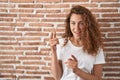 Young caucasian woman standing over bricks wall background pointing fingers to camera with happy and funny face Royalty Free Stock Photo