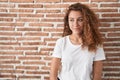 Young caucasian woman standing over bricks wall background smiling looking to the side and staring away thinking Royalty Free Stock Photo