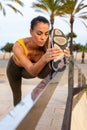 Young caucasian woman stretching leg before running. Beach background with palm trees. Vertical image. Royalty Free Stock Photo