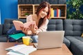 Young caucasian woman student sitting on sofa reading book at home Royalty Free Stock Photo