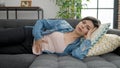 Young caucasian woman suffering for stomach ache lying on sofa at home Royalty Free Stock Photo