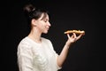 Young caucasian woman with tail eating piece of pizza. Royalty Free Stock Photo