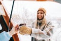 Young caucasian woman taking mug with hot tea near van , in winter time outdoor, during road trip Royalty Free Stock Photo