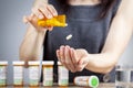 A young caucasian woman is taking a pill out of the medication bottle