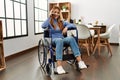 Young caucasian woman talking on smartphone sitting on wheelchair at home Royalty Free Stock Photo
