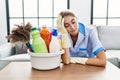 Young caucasian woman tired wearing cleaner uniform at home
