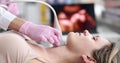 Young caucasian woman undergoes ultrasound of thyroid gland in office of female doctor