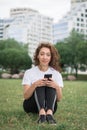 Young caucasian woman using her smartphone for internet surfing lying on a green grass Royalty Free Stock Photo