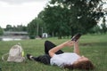 Young caucasian woman using her smartphone for internet surfing lying on a green grass Royalty Free Stock Photo