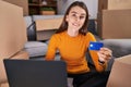 Young caucasian woman using laptop and credit card sitting on floor at new home Royalty Free Stock Photo