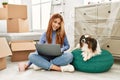 Young caucasian woman using laptop sitting on floor with dog at new home Royalty Free Stock Photo