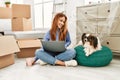 Young caucasian woman using laptop sitting on floor with dog at new home Royalty Free Stock Photo