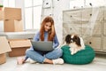 Young caucasian woman using laptop sitting on floor with dog at new home Royalty Free Stock Photo