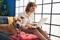 Young caucasian woman using laptop sitting on sofa with dog at home Royalty Free Stock Photo