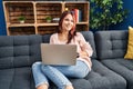 Young caucasian woman using laptop sitting on sofa at home Royalty Free Stock Photo