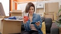 Young caucasian woman using smartphone drinking coffee at new home Royalty Free Stock Photo