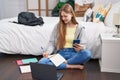 Young caucasian woman using smartphone and laptop writing on notebook at bedroom Royalty Free Stock Photo
