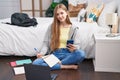 Young caucasian woman using smartphone and laptop writing on notebook at bedroom Royalty Free Stock Photo